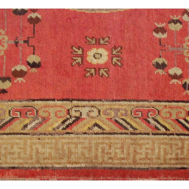 An early 20th century Central Asian Khotan rug with multiple central medallions on a pink background surrounded by...