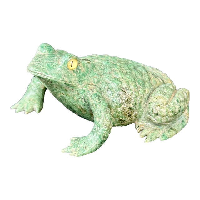 A charming carved frog in mottled green hardstone, likely serpentine, with a naturalistic, sculptural presence. The...