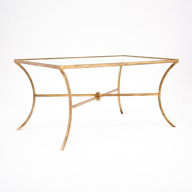 Coffee table from France, in the mid-century modern style. The rectangular top is glass, with a gold leafed trim while the...