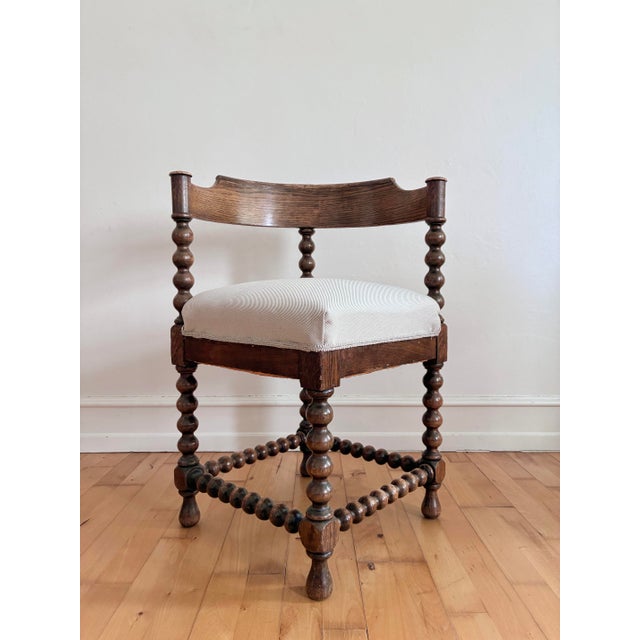 A pair of antique corner chairs in solid wood, likely beech, with a dark stained finish. These English chairs feature...