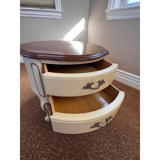 Elegant cream-colored cabinet with a beautiful brown top. Features two drawers with softly rounded corners, giving the...