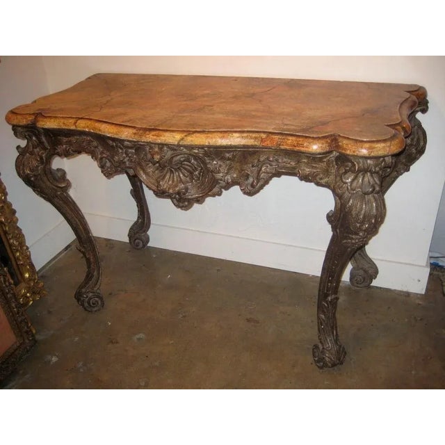 Large hand carved, turn-of-the-century, wood console from Florence, Italy. The richly carved, silver gilt body is adorned...