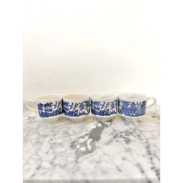 Navy blue ceramic chinoiserie coffee cup set of four. Features Asian motifs of pagodas, birds, and boats.