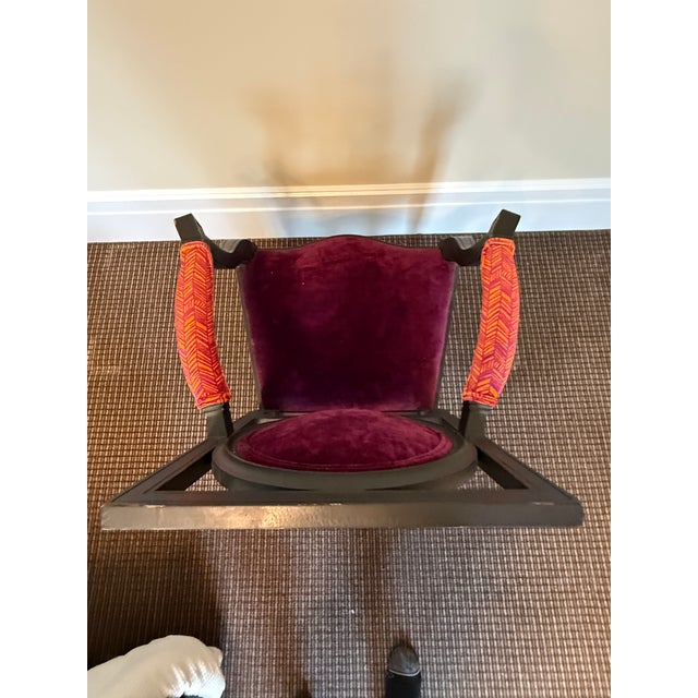Regency style ebonized and gilt accented armchair with fuchsia and purple fabric.