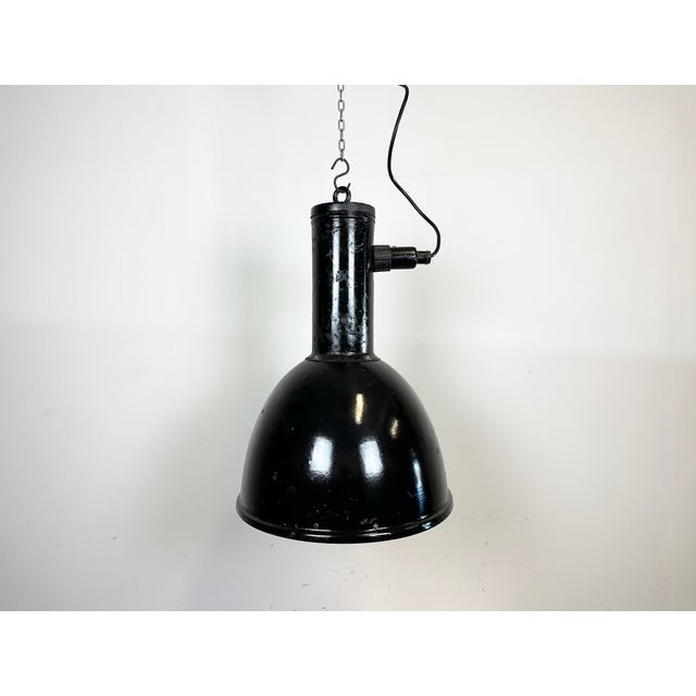 Industrial factory pendant light made in former Czechoslovakia during the 1950s. It features black enamel shade with white...