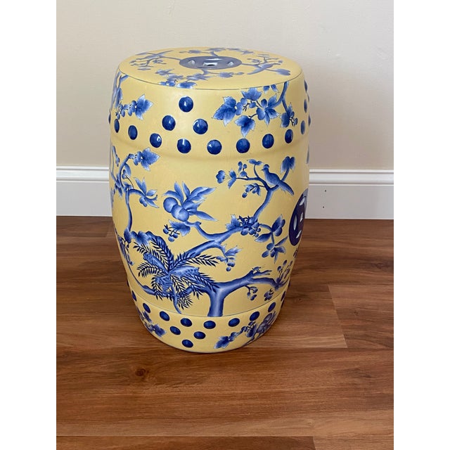 A glazed ceramic garden stool with cobalt blue chinoiserie decoration against a warm yellow ground. Birds, flowering...