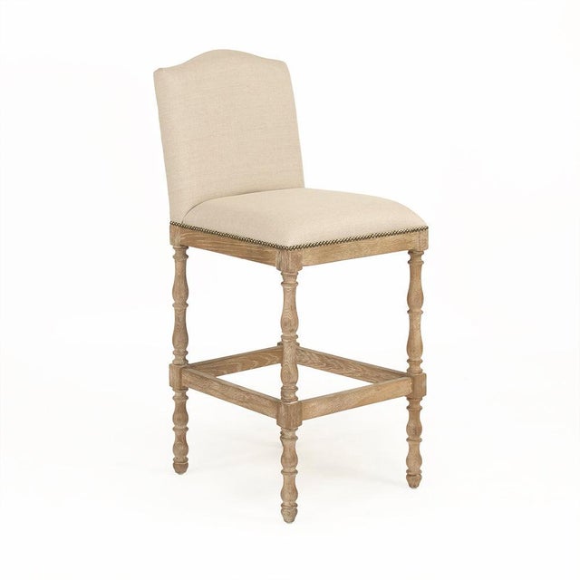 The Aria Bar Stool from Zentique is a French country bar stool with a padded linen seat on a recycled oak frame with...