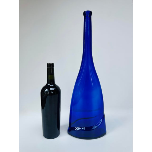 Tall cobalt blue glass vase with an unusual flattened bottle form and sweeping molded fold across the lower body. The...
