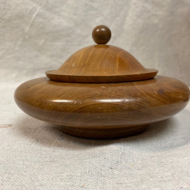 Minimalist aesthetic with a smooth, natural finish highlighting the Myrtlewood grain and a small, round knob on the lid....