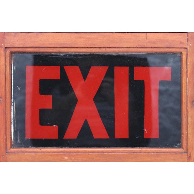 Vintage exit sign framed in cherry stained carved wood, with Neoclassical architectural motifs and scroll shaped corbels...