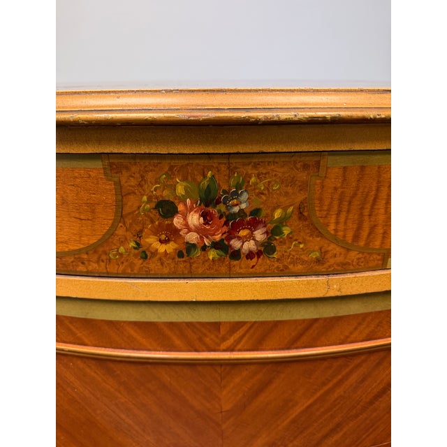 Elegant vintage Neoclassical demilune chest featuring richly figured wood veneer, decorative gilt accents, fluted...