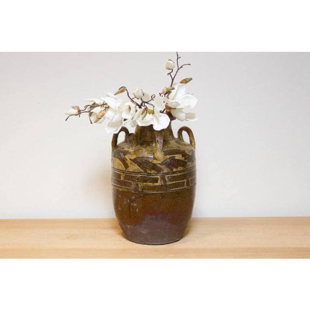 This decorative earthenware jar from the early 20th century, features a two-tone brown color, floral and geometric...