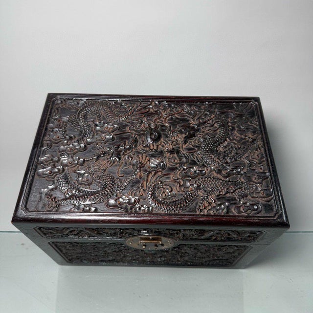Solid hardwood storage chest heavily carved with dynamic twin dragons chasing flaming pearls amid swirling cloud patterns,...