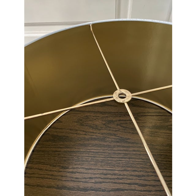 Substantial glossy white parchment tapered drum lamp shade with a reflective gold interior that casts a warm, illuminating...