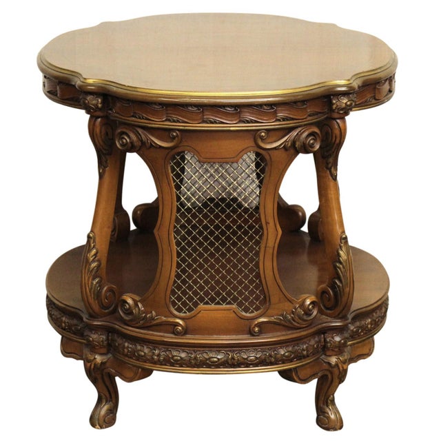French style dark tone wooden side table with ornate carved details, a round top, and metal grid details on the side. Age...