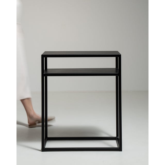This early 21st century side table from Poland is finished in black, worked in wood. Its form follows honest, well-...