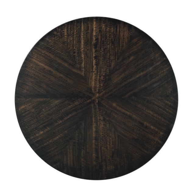 A round top is veneered with rich eucalyptus veneer in a radiant pattern above six gracefully tapering saber legs that are...