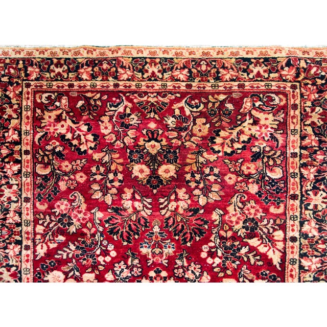 A classic early 20th century Persian Sarouk rug with an all-over mirrored pattern containing myriad floral clusters,...