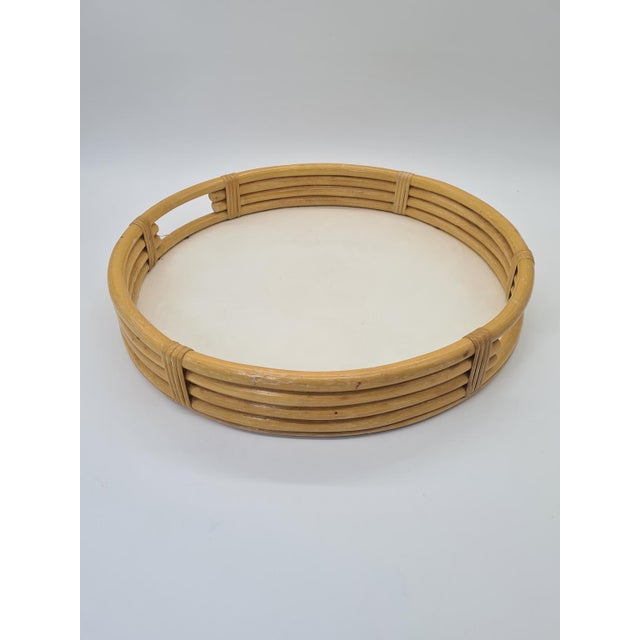 A stylish, round tray made of bent rattan (bamboo) with a wooden panel insert. Its classic form and natural material evoke...