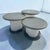 Set of three frosted lucite with stone top circular nesting tables. Each table has black acrylic bottoms with frosted...