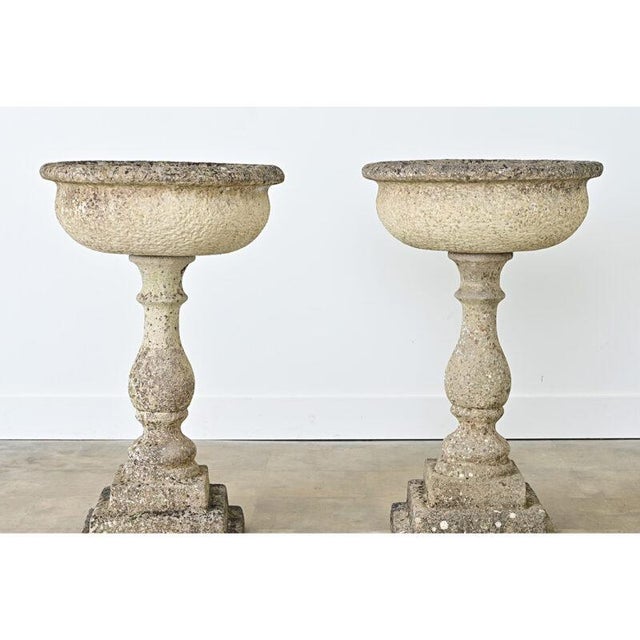 English, late 19th century pair of garden urns on architectural pedestal bases made of cast, reconstituted stone. The...