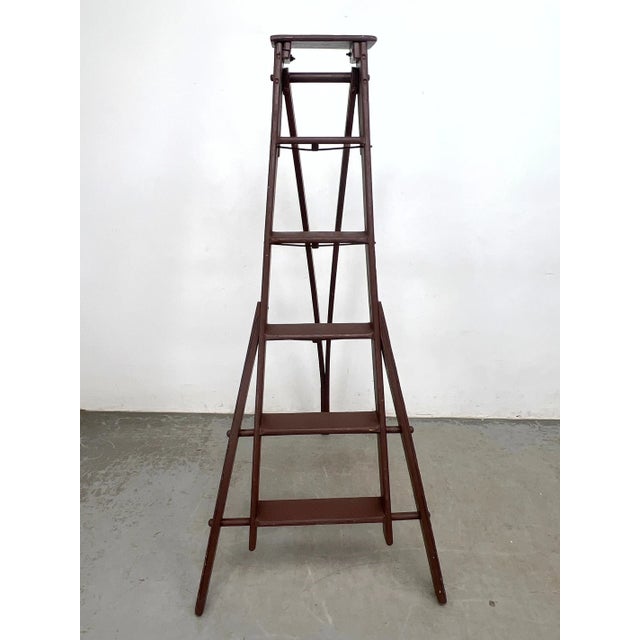 Wooden folding library ladder with tiered steps. Dark painted finish. A-frame construction with hinged top and spreader...