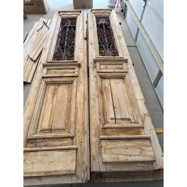 Beautiful pair of antique solid wooden doors,featuring intricate wrought iron grilles, raised panels,opening windows,and...
