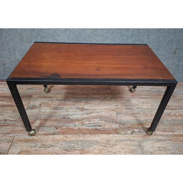 Modernist style coffee table, combining a solid wood top with a black lacquered metal frame, resting on four straight legs...