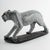 A finely carved soapstone figure of a leopard depicted in a prowling stance, the elongated body striding across a textured...