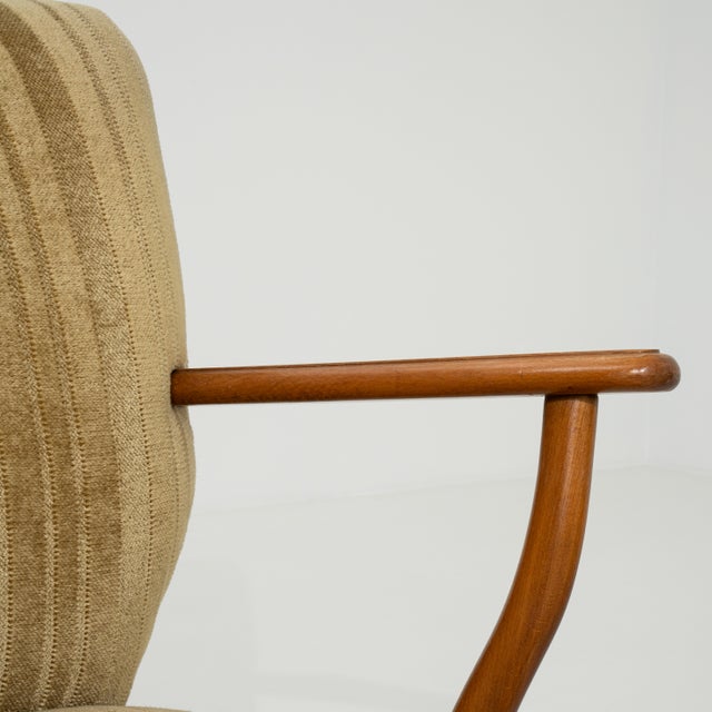 A set of three mid-century modern armchairs with wooden frames and upholstered seats. The design features clean lines and...