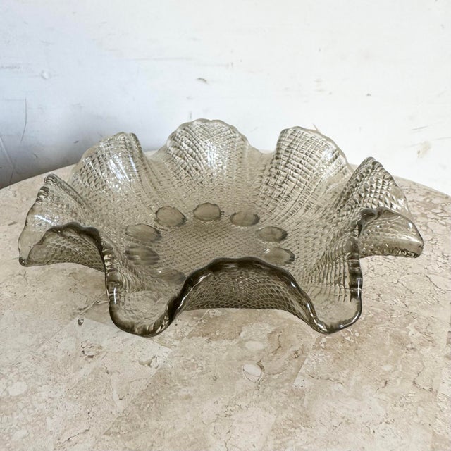 This Vintage Smoked Glass Dish serves as a stylish catchall or display piece with its elegant, ruffled edges and textured...