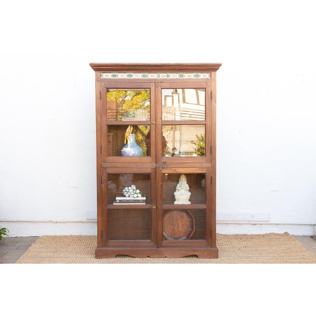 This 70-inch tall cabinet is a classic example of British Colonial furniture from the early 20th century. It features a...