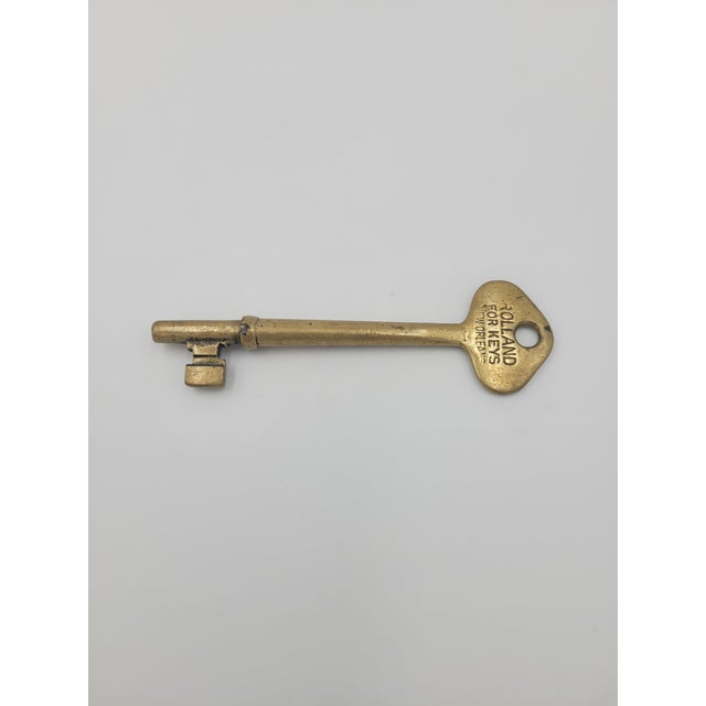 This is a beautiful, authentic antique brass barrel key featuring an embossed bow stamped with "ROLLAND FOR KEYS NEW...