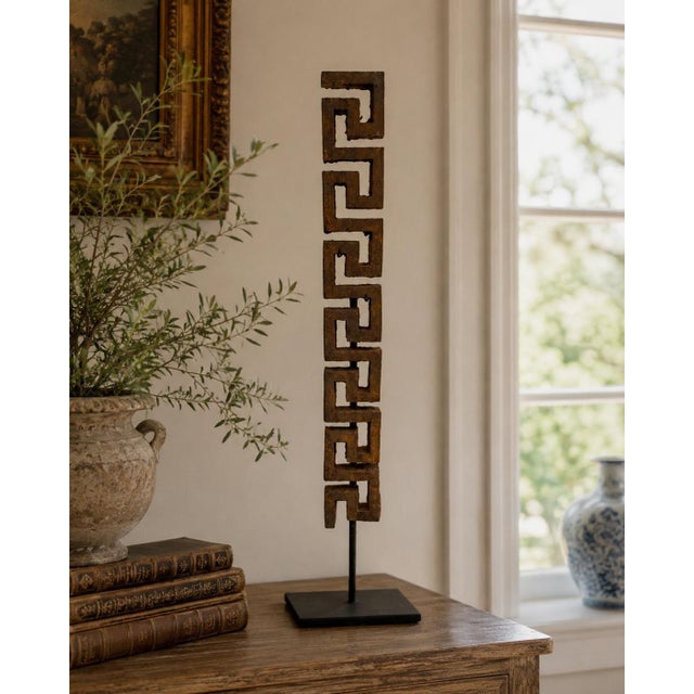 An early-20th-century iron architectural fragment composed of a continuous Greek key motif, now presented vertically on a...