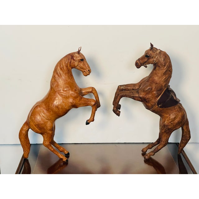 Handsome pair of leather bound horse sculptures, the darker one with more detailed work and glass eyes.