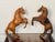 Handsome pair of leather bound horse sculptures, the darker one with more detailed work and glass eyes.