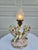 This fanciful cherub with lyre, set against a double cornucopia of flowers, is truly beautiful to behold. The lamp...