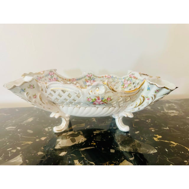 A stunning antique Dresden porcelain centerpiece bowl featuring intricate reticulated "lace" sides and hand-painted floral...