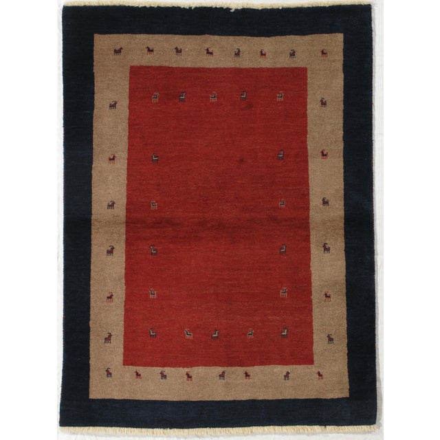 Vintage hand-knotted Persian Lori Gabbeh wool rug with a red field featuring small stylized animal motifs arranged in an...