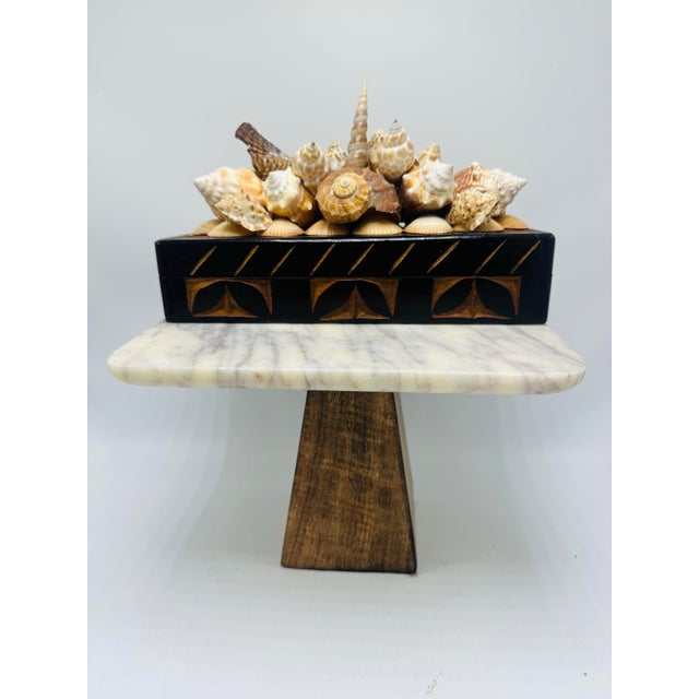 This carved wooden box is a striking piece, combining natural materials and intricate craftsmanship. The base of the box...