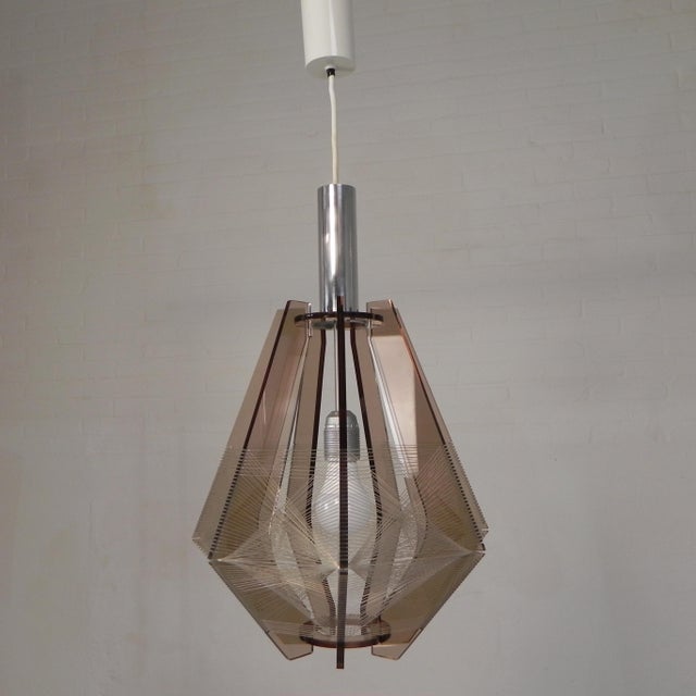 The lamp consists of a transparent acrylic glass frame covered with nylon thread. The nylon forms a kind of geometric...