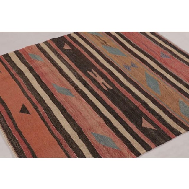 Handwoven in wool and originating circa 1950-1960, this 5x5 vintage Persian kilim is a rare square tribal curation from...