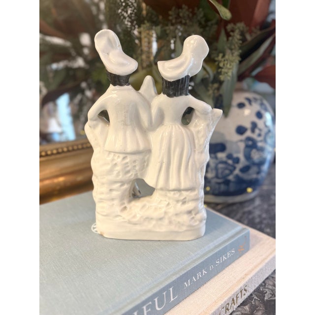 This antique Staffordshire piece depicts a charming man and woman all in white attire and playful hats. Measuring...