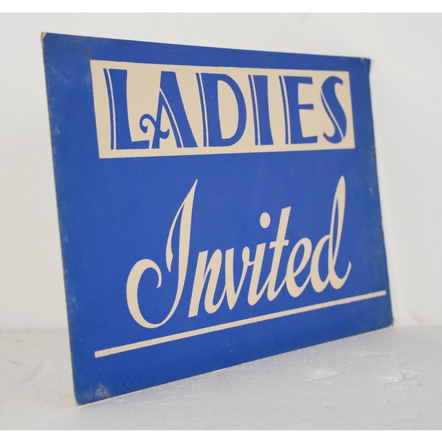 Vintage retail cardboard wall sign with a blue background and white lettering. The sign reads, Ladies Invited". Good...