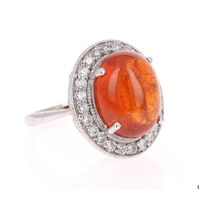 This stunner has a large Cabochon Oval Cut Mandarin Garnet that weighs 16.16 Carats and is surrounded by 24 Round Cut...