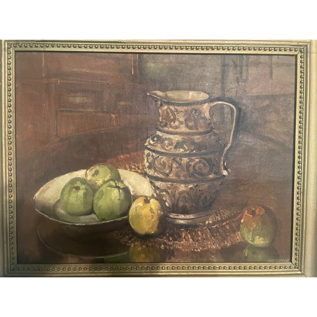 Antique framed still life painting depicting a decorative jug and a bowl of green and yellow apples. Features intricate...
