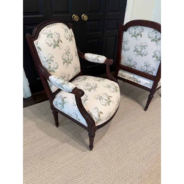 A refined pair of carved wood frames with fluted legs and classic French detailing. Newly upholstered in Colefax & Fowler...