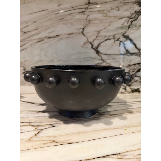 Large black glazed bowl rimmed with orbs.
