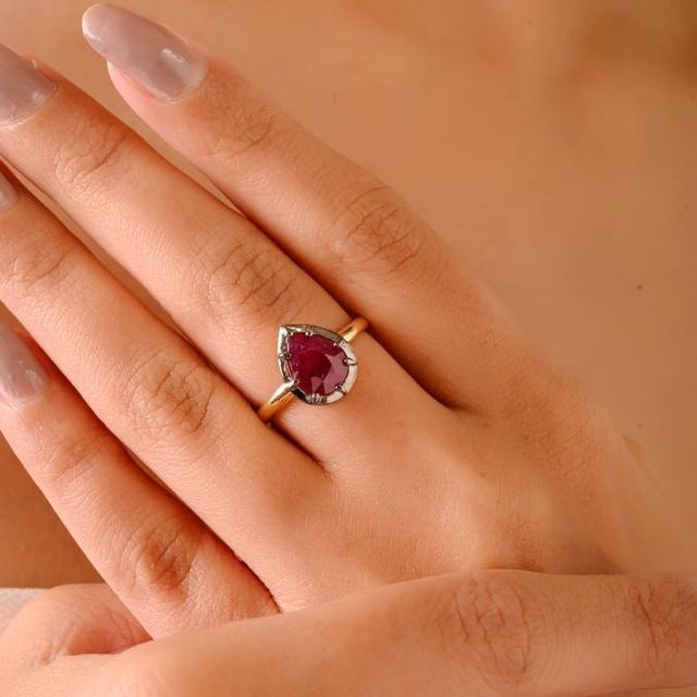 This elegant antique-style ring showcases a stunning pear-cut natural ruby weighing 2.39 carats, set in 18K yellow gold...