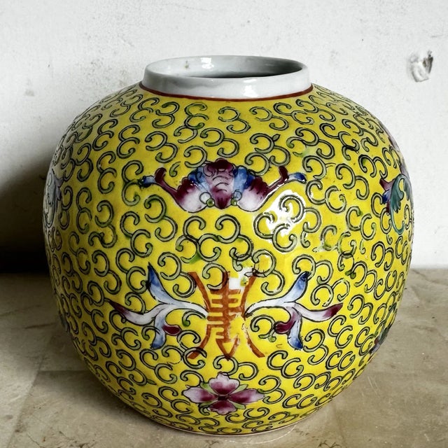 This vintage Chinese porcelain vessel is rendered in the classic famille rose palette, featuring a luminous yellow ground...